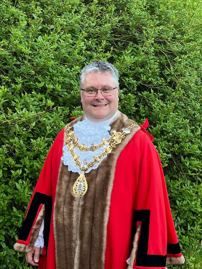 picture of smiling man in in mayoral attire and chains