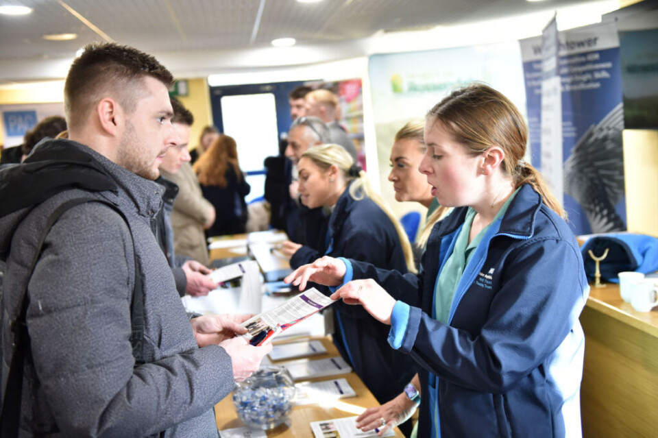 woman talking to a man at a jobs fair showing a leaflet and discussing it