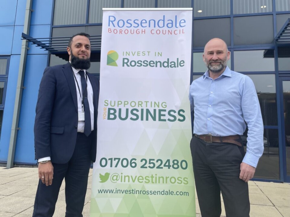 Tariq Ali and Davis Smurthwaite stood infront of a banner that says INVEST IN ROSSENDALE