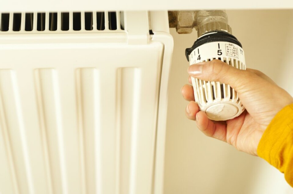 a hand turning the dial on a radiator thermostat